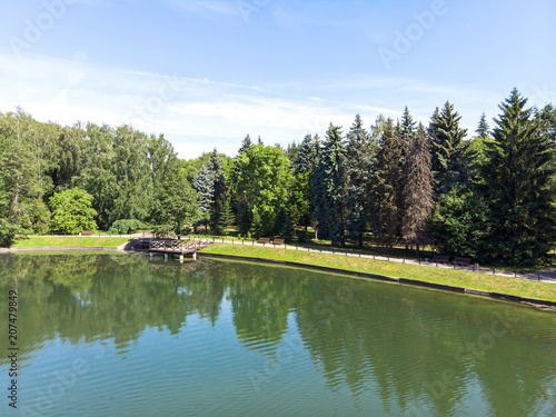 spring landscape of the pond with wooden pier and blue sky with clouds