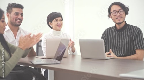 Business meeting. Small start up business meeting in room. Asian team with indian man brainstorming the next big idea, clapping. New business model start up concepts.