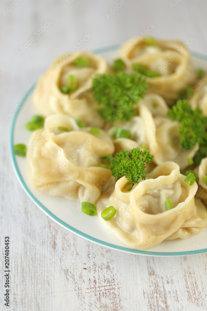 dumplings.  Manty with greens in a round plate on shabby chic background . Manti . Traditional meat dish