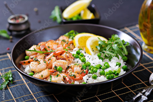 Rice with young green peas, shrimps and arugula in black bowl. Healthy food. Buddha bowl