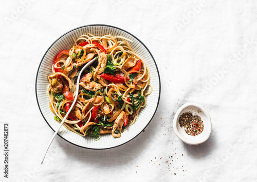 Teriyaki chicken, bell peppers, onions, spinach and rice noodles stir fry on white background, top view. Asian style healthy food photo