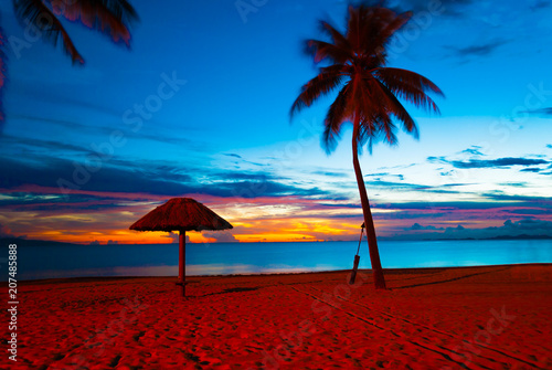 Enjoying quiet calm sunset with empty umbrella at a sandy beach in Fiji