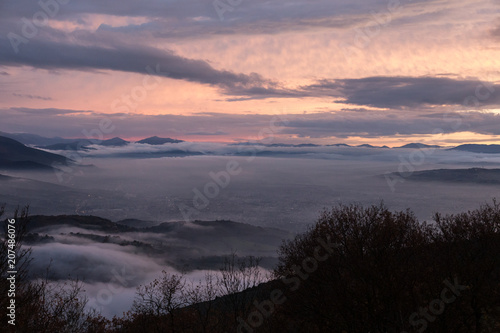 Umbria valley in winter filled by mist at sunset, with emerging 