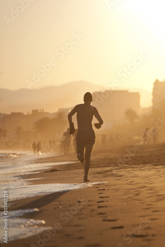 Young man jogging at the beach.