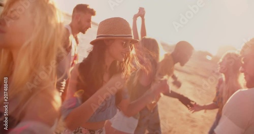 Multi-ethnic hipster friends dancing at summer beach party at sunset