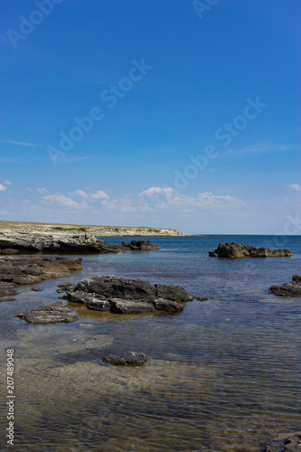 Rocks and stones on the background of the sea under the blue sky.