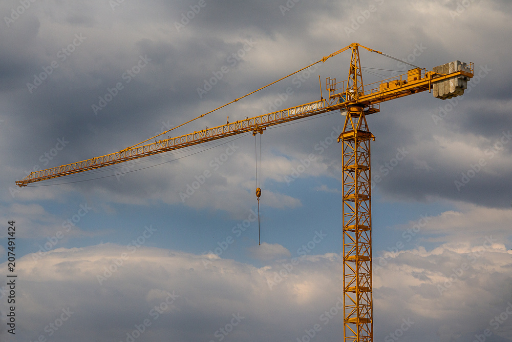 Yellow construction crane against the background of the sky. Construction
