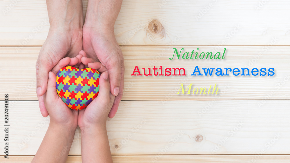 Obraz premium National Autism Awareness month concept with puzzle or jigsaw pattern on heart with autistic child's hands supported by nursing family caregiver