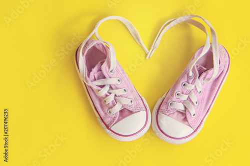 top view of little sneakers for baby on yellow background, fashion lifestyle