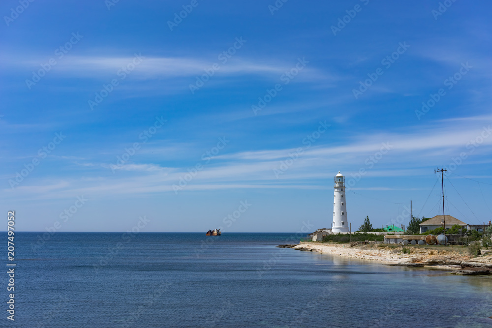 seascape with beautiful white lighthouse on blue sky background.
