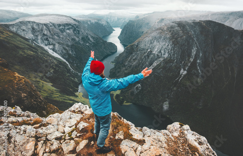 Brave traveler man raised hands traveling in Norway standing on cliff mountain active lifestyle weekend getaway adventure vacations success concept aerial Naeroyfjord landscape photo