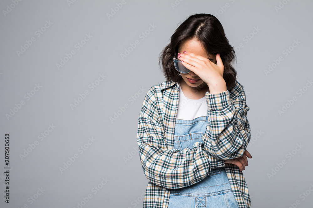 Portrait of young scared woman covering eyes with hands while standing against gray studio background. Confused girl close eyes with palms ignoring something Portrait of young scared woman covering eyes with hands while standing against gray studio background. Confused girl close eyes with palms ignoring something