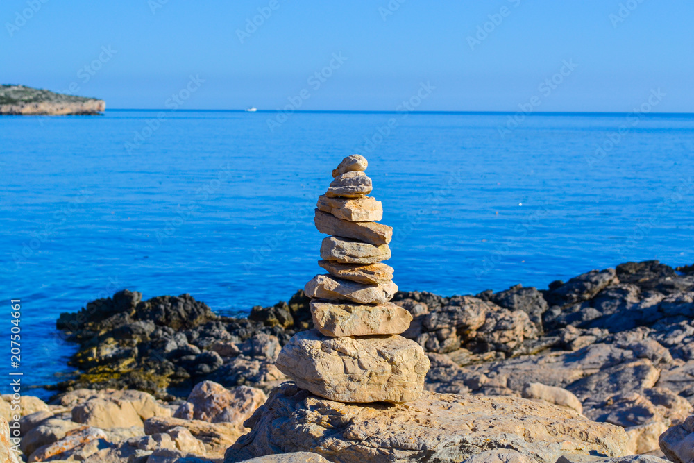 Calm pile of stones balance on a rock, in perfect harmony with the ocean background