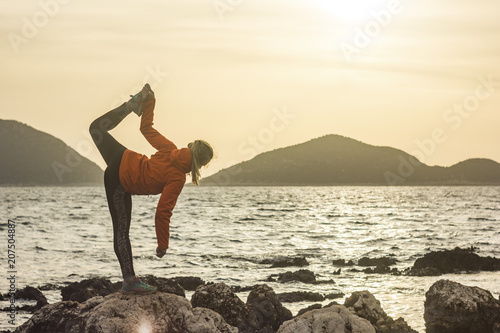 girl making yoga on a cliff near mediterranean sea at sunrise