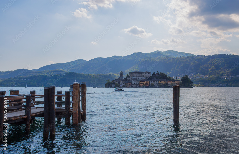 View of San Giulio island from Orta San Giulio, Novara province, Italy. it is part of the circuit of the most beautiful villages in Italy and is awarded the orange flag by the Italian Touring Club. View of San Giulio island from Orta San Giulio, Novara province, Italy. it is part of the circuit of the most beautiful villages in Italy and is awarded the orange flag by the Italian Touring Club.