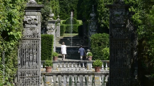 A glimps of the park of Villa Reale in Marlia, Lucca. An old iron gate opens to the formal garden. Tourist walking on the avenue. photo