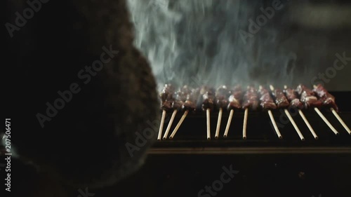 Girl gently turning arrosticini on the grate to cook them properly.