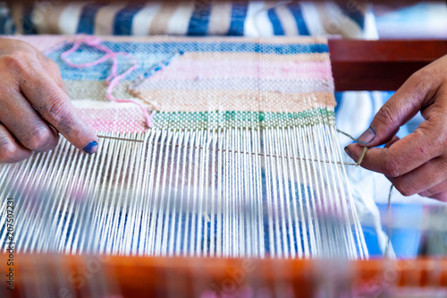 Close Up Hand of Woman Worker Use Needle for Weaving Loom Linen to Weaving machine and Thai traditional Linen.