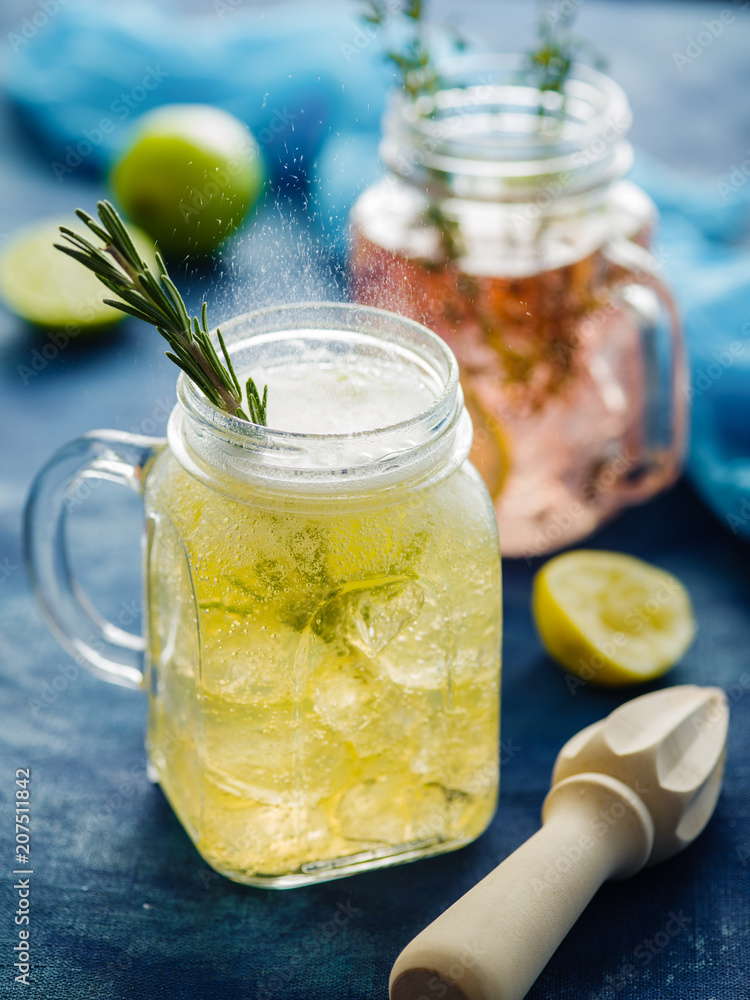 Homemade Iced fizzy Sparkling lemonade with lemon, rosemary and thyme in Mason jar. Homemade Iced fizzy Sparkling lemonade with lemon, rosemary and thyme in Mason jar.