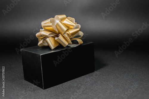 black box tied with golden ribbon on a black background