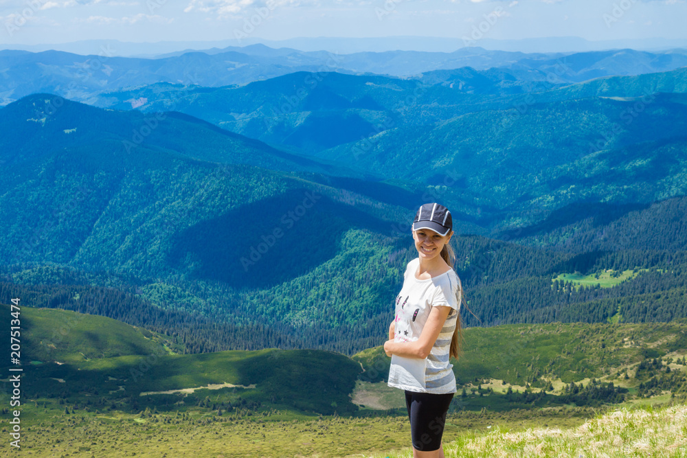 Young happy woman on top of hill enjoy beautiful view of sky and mountains, freedom and harmony concept