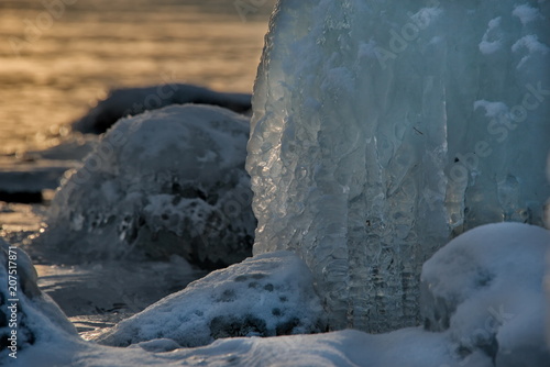 Russia. mountain Altai. Evening light in ice floods and icicles on the shore of lake Teletskoye.