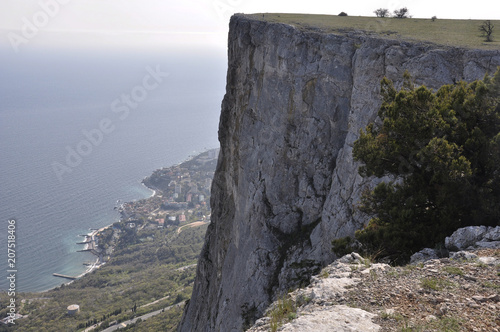 Foros in the Crimea on the mountain top. Landscape of the high rock, blue ocean and the city at the coastline. Seascape from the green cliff. Extreme hiking