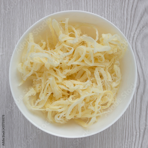 Dried squid shavings in a white Cup close-up on a light wooden background