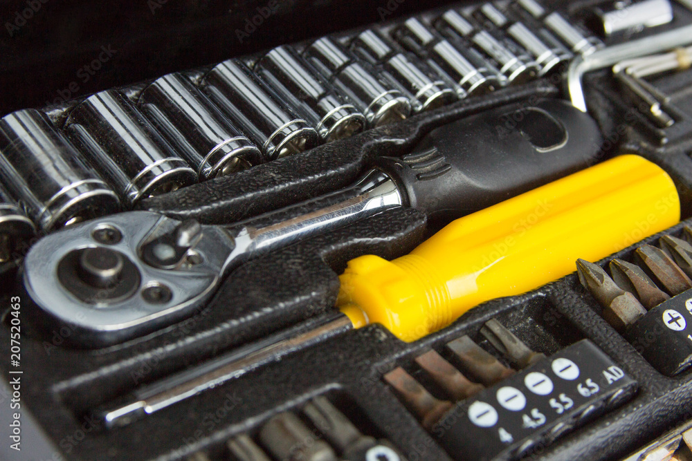 Fototapeta premium black metal tool box, yellow screwdriver and replaceable nozzles