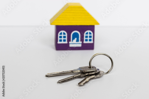 Three metal keys and a purple toy house with a yellow roof on a white background © Людмила Ильина