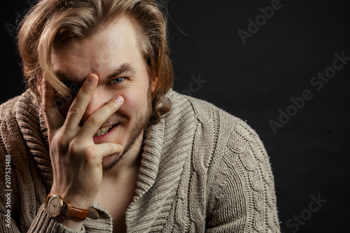 close up portrait of brutal man laughing and closing his face with hand in the studio. isilated black background. copyspace photo