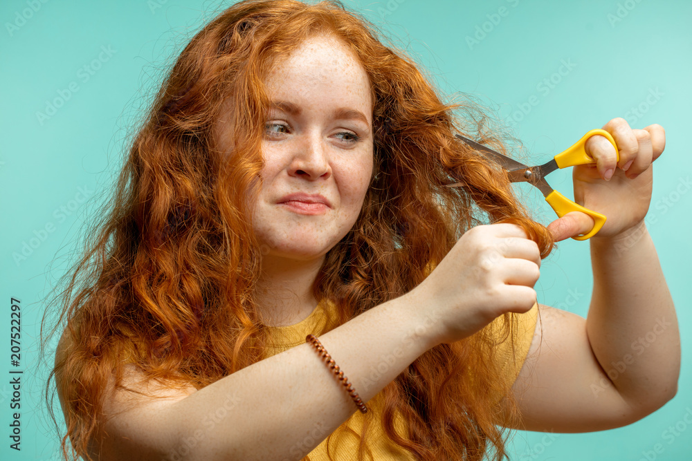 Redhaired woman cutting her damaged dry hair with scissors isolated over  blue background. Hair Repair Treatment Cure Stock Photo | Adobe Stock