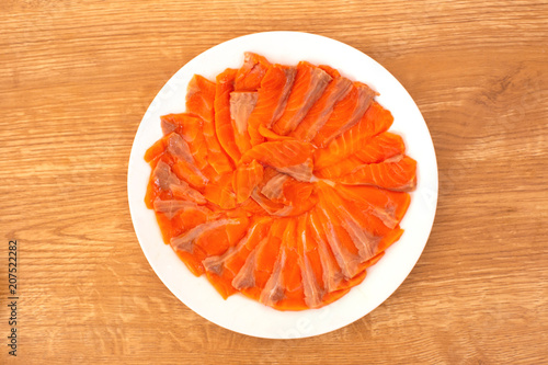 Raw sliced sashimi salmons are arranged in white plate on wood background and ready to serve for customer. 