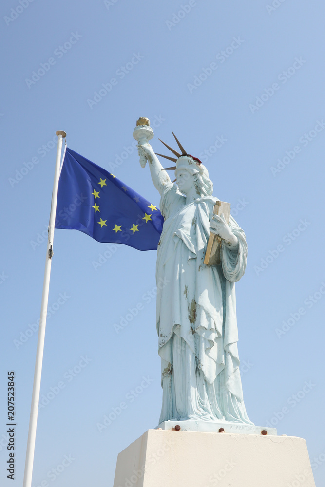 usa statue of liberty with the flag of europe in the wind concept of economiqyue and military alliance