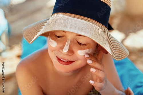 Facial Care. Female Applying Sun Cream and Smiling. Beauty Face.  Portrait Of Young Woman in hat Smear  Moisturizing Lotion on Skin. SkinCare