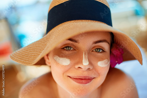 Woman smile applying sun cream  on face. Skincare. Body Sun protection. sunscreen. Female in hat smear  moisturizing lotion on skin.