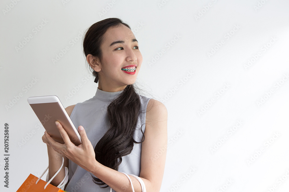 Happy young woman holding shopping bags and mobile phone. Makes online shopping on a tablet. Happy young woman holding shopping bags and mobile phone. Makes online shopping on a tablet.