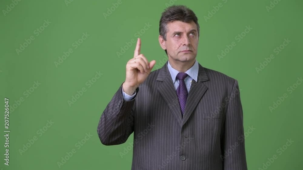 Mature handsome businessman against green background Mature handsome businessman against green background