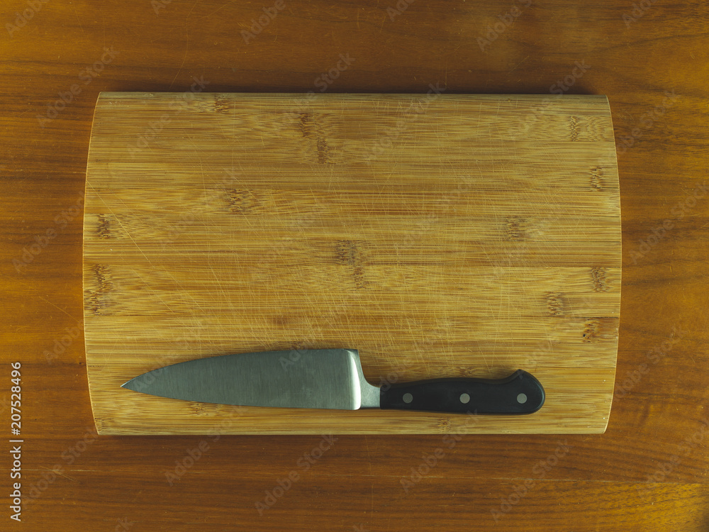 Wooden cutting board with a knife resting on a wooden table