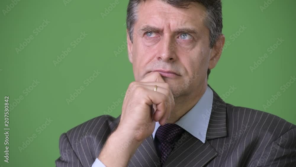 Mature handsome businessman against green background Mature handsome businessman against green background
