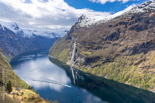 View of Geirangerfjord and Skageflå mountain farm with a boat and the Seven Sisters waterfall in the background, Norway
