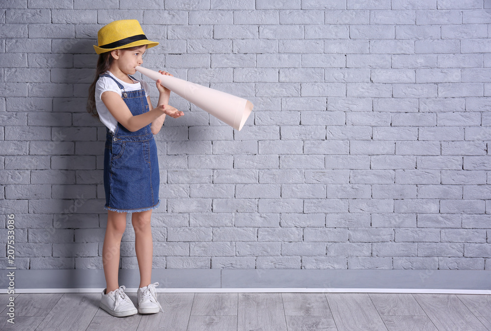 Adorable little girl with paper megaphone on brick wall background Adorable little girl with paper megaphone on brick wall background