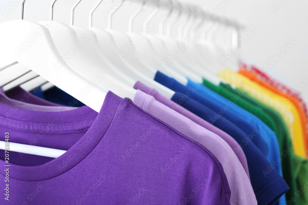 Obraz premium Rack with rainbow clothes on light background