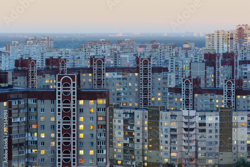 Urban view of many apartment buildings at dusk with lights switched on inside. Densely populated residential district of Troieshchyna  neighborhood of Kiev  Ukraine