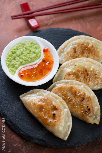 Close-up of pan fried korean potstickers served with dipping sauces, vertical shot, selective focus