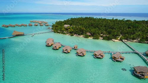 Aerial view of Motu Tautau, palm trees on little islets and turquoise water of blue lagoon, over water bungalows, tropical paradise of South Pacific Ocean - Tahaa island, seascape of French Polynesia photo