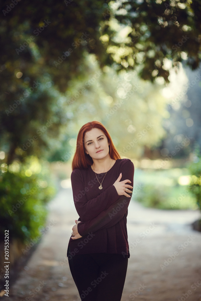 Beautiful red-haired young woman is walking in the autumn park Beautiful red-haired young woman is walking in the autumn park