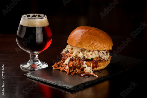 Pulled pork and coleslaw sandwich with a glass of red beer