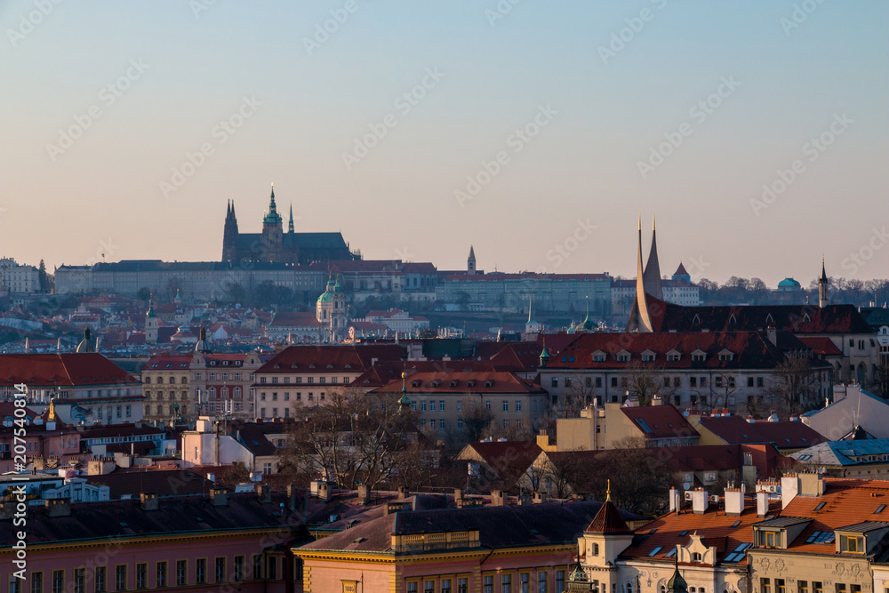 Prague cityscape with red tile roofs, St Vitus Cathedral and Hradcany Castle. Scenic spring sunset in town
