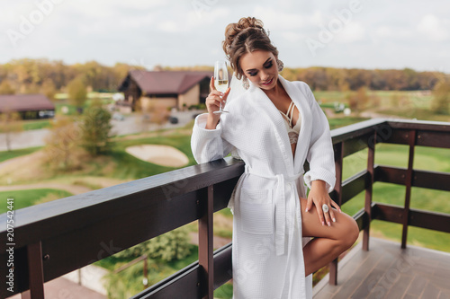 beautiful woman in lingerie and bathrobe enjoying a drink in a glass photo
